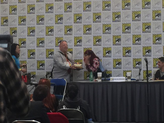 Brian Michael Bendis presenting Kelly Sue DeConnick with a birthday cake.