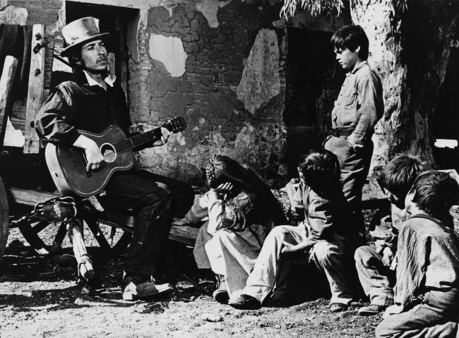 Bob Dylan performing for some children on the set of 'Pat Garrett & Billy the Kid'.