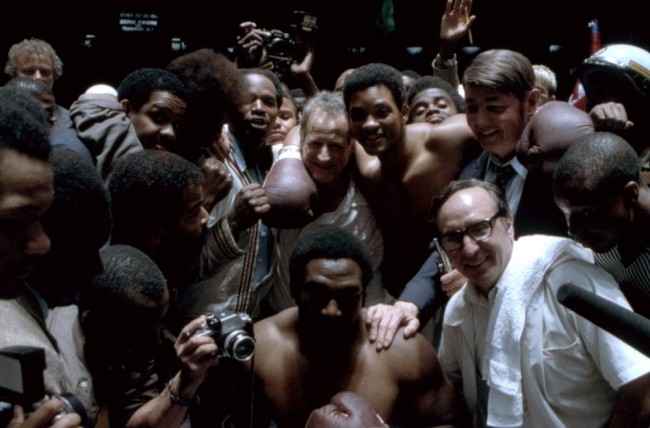 ALI, front row, center: Jamie Foxx, Ron Silver, second row: director Michael Mann, Will Smith as Muhammad Ali, Jon Voight, on set, 2001. © Columbia Pictures.